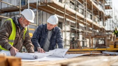 Mestre de obras e operário analisando a planta no canteiro, sob supervisão da Construtora Especializada.