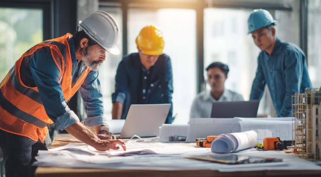 Equipe da Construtora Especializada analisando plantas e projetos em reunião.