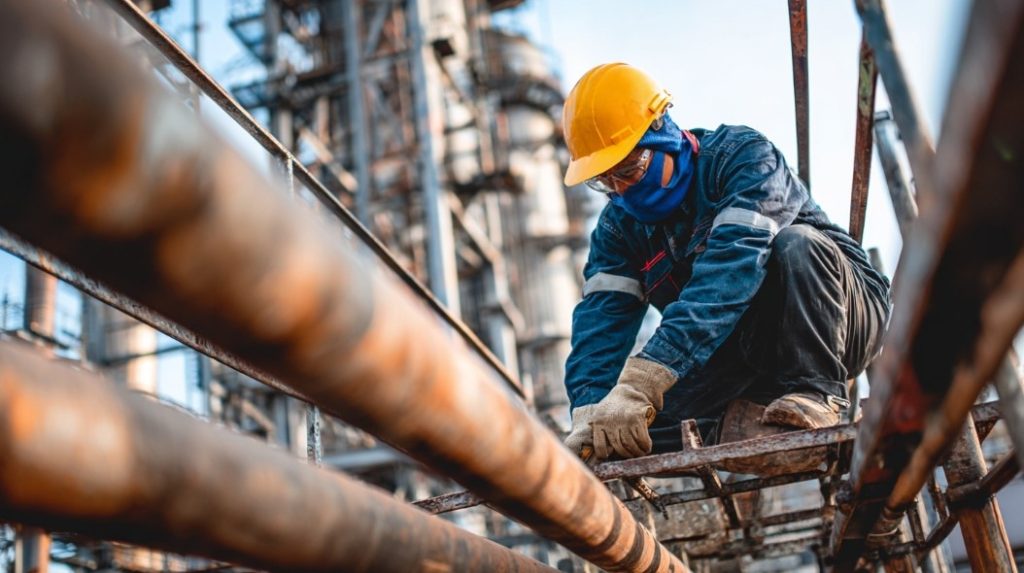 Trabalhador concentrado em manutenção de tubulação, foco da Construtora Especializada em segurança.