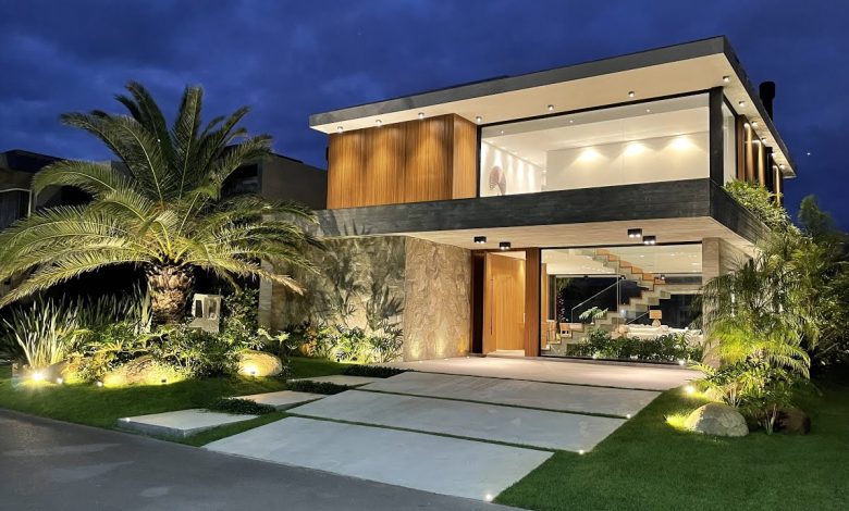 Fachada noturna de Construção de Alto Padrão com jardim iluminado.