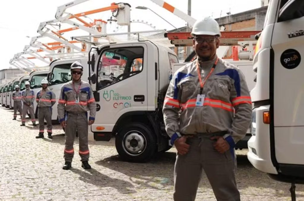 Equipe de Eletricistas da Enel em frente à frota de caminhões de serviço.