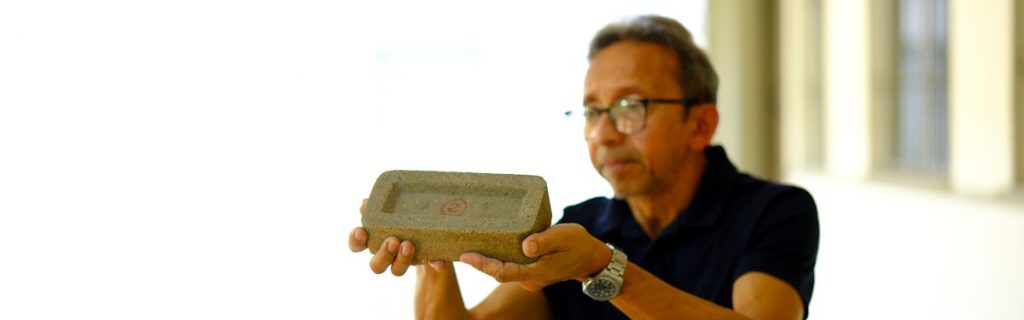 Pesquisador segurando tijolo sustentável feito com bagaço da cana-de-açúcar.
