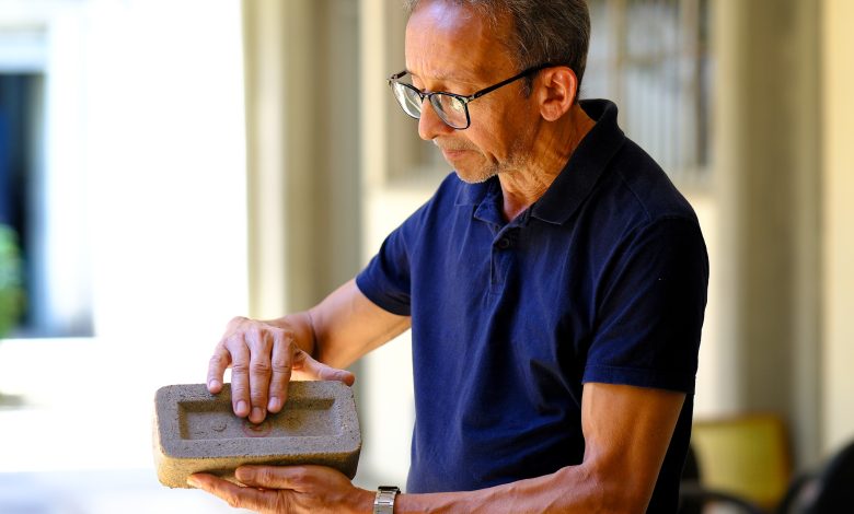 Pesquisador segurando tijolo sustentável feito com bagaço da cana-de-açúcar.