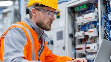 Eletricista testando painel de controle com laptop, foco em segurança e qualidade.