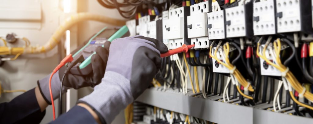 Eletricista Comercial testando relés de contato no quadro de distribuição.