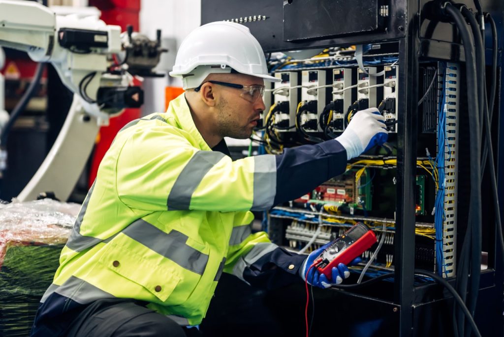 Eletricista Comercial testando painel de comando com multímetro digital.